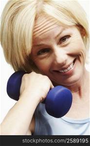 Portrait of a mature woman exercising with a dumbbell and smiling