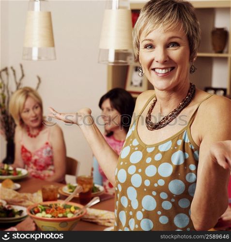Portrait of a mature woman gesturing and her friends sitting at the dining table in the background