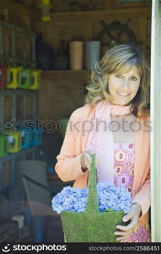 Portrait of a mature woman holding a basket of flowers and smiling