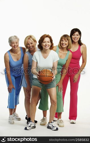 Portrait of a mature woman holding a basketball with her four friends standing behind her