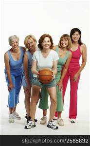 Portrait of a mature woman holding a basketball with her four friends standing behind her