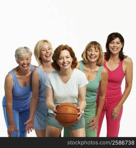 Portrait of a mature woman holding a basketball with her four friends standing behind her