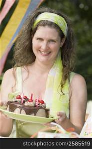 Portrait of a mature woman holding a birthday cake and smiling