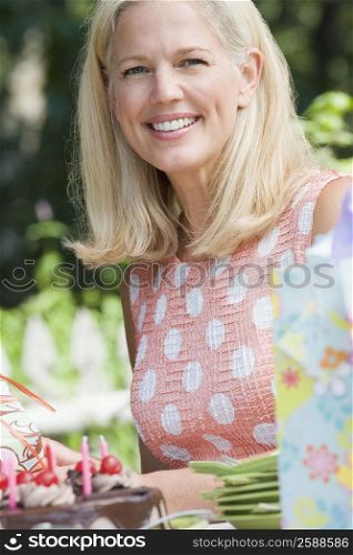 Portrait of a mature woman holding a birthday cake and smiling
