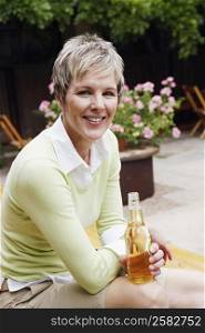 Portrait of a mature woman holding a bottle of wine and smiling