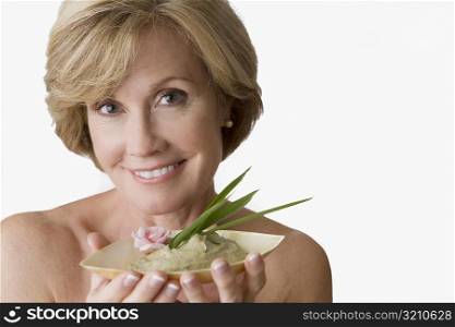 Portrait of a mature woman holding a bowl of face pack