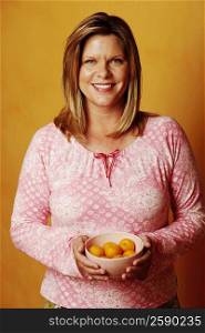 Portrait of a mature woman holding a bowl of peaches and smiling