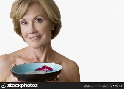 Portrait of a mature woman holding a bowl of water with floating petals