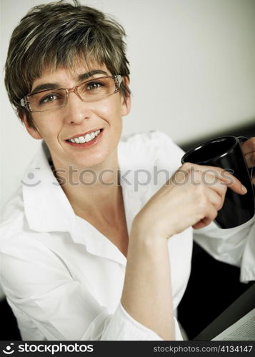 Portrait of a mature woman holding a cup of coffee and smiling