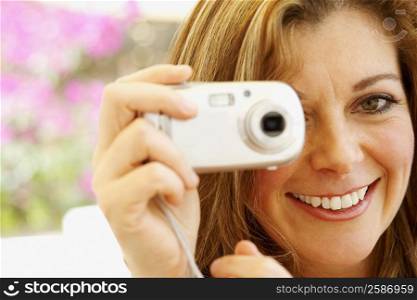 Portrait of a mature woman holding a digital camera and smiling