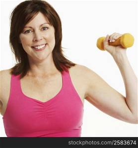Portrait of a mature woman holding a dumbbell and smiling