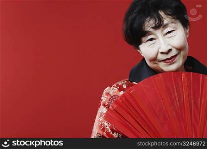 Portrait of a mature woman holding a folding fan