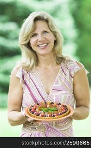 Portrait of a mature woman holding a fruit tart
