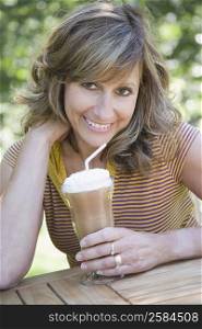 Portrait of a mature woman holding a glass of chocolate milkshake