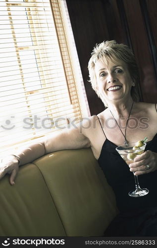 Portrait of a mature woman holding a glass of cocktail and smiling