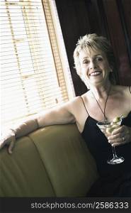 Portrait of a mature woman holding a glass of cocktail and smiling