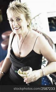 Portrait of a mature woman holding a glass of cocktail and smiling