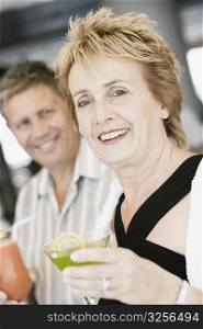 Portrait of a mature woman holding a glass of cocktail with a senior man beside her