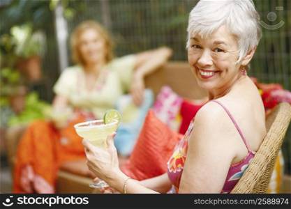 Portrait of a mature woman holding a glass of lemonade and smiling