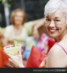 Portrait of a mature woman holding a glass of lemonade and smiling