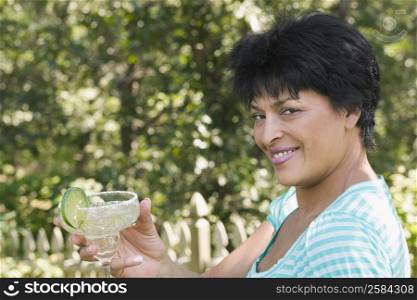 Portrait of a mature woman holding a glass of margarita and smiling
