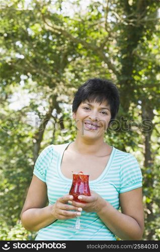 Portrait of a mature woman holding a glass of smoothie and smiling