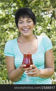 Portrait of a mature woman holding a glass of smoothie and smiling