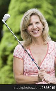 Portrait of a mature woman holding a golf club and smiling