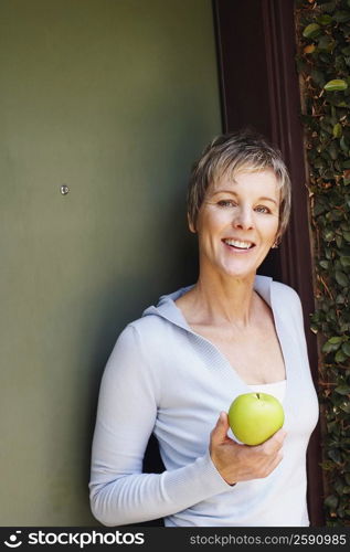 Portrait of a mature woman holding a granny smith apple