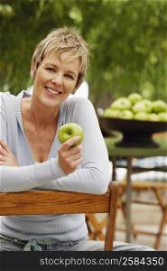 Portrait of a mature woman holding a granny smith apple and smiling