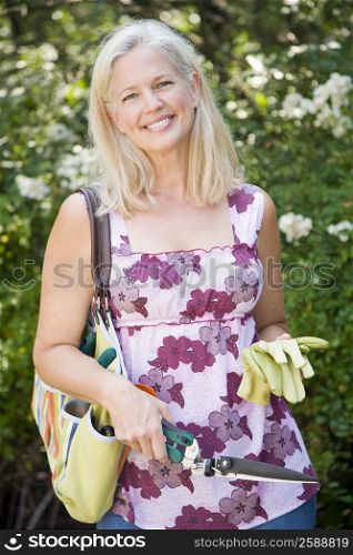 Portrait of a mature woman holding a hedge clipper and a pair of gardening gloves
