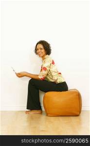 Portrait of a mature woman holding a mobile phone and sitting on a cushion