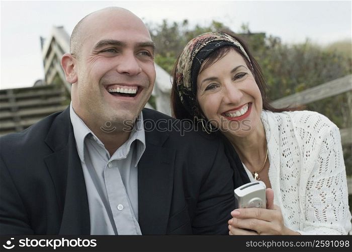 Portrait of a mature woman holding a mobile phone and smiling with a mid adult man
