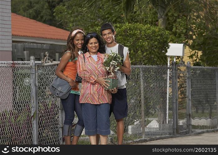 Portrait of a mature woman holding a money tree while standing with her daughter and son