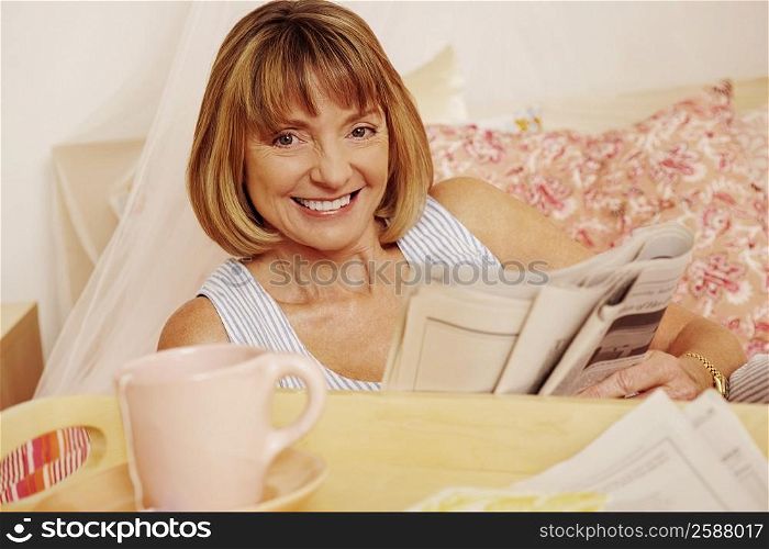Portrait of a mature woman holding a newspaper and smiling