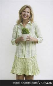 Portrait of a mature woman holding a potted plant and smiling