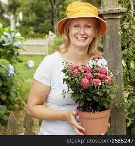 Portrait of a mature woman holding a potted plant and smiling