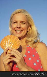 Portrait of a mature woman holding a seashell and smiling