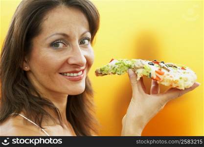 Portrait of a mature woman holding a slice of pizza