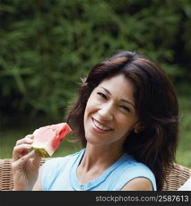 Portrait of a mature woman holding a slice of watermelon and smiling