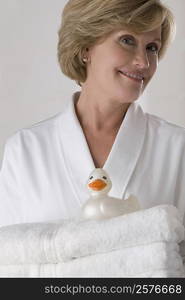 Portrait of a mature woman holding a stack of folded towels and smiling