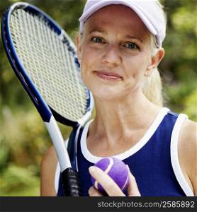 Portrait of a mature woman holding a tennis racket and a tennis ball
