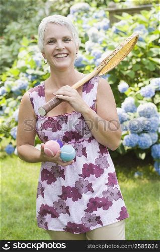 Portrait of a mature woman holding a tennis racket and tennis balls