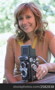 Portrait of a mature woman holding a TLR camera and smiling