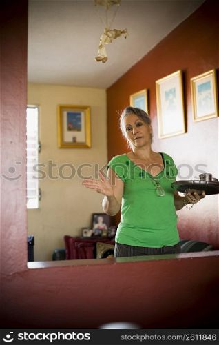 Portrait of a mature woman holding a tray and gesturing