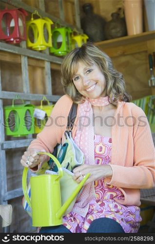 Portrait of a mature woman holding a watering can in a store and smiling