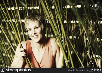 Portrait of a mature woman holding bamboo plants and smiling