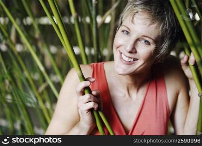 Portrait of a mature woman holding bamboo plants and smiling