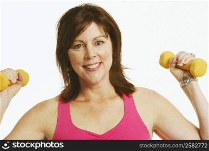 Portrait of a mature woman holding dumbbells and smiling