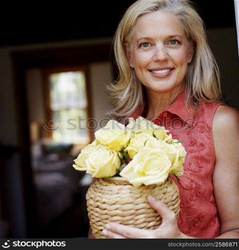 Portrait of a mature woman holding flowers in a vase and smiling